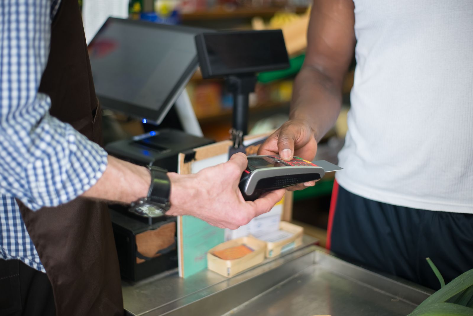 Customer paying by card at a retail store checkout, used to measure sales based Earned Media Value